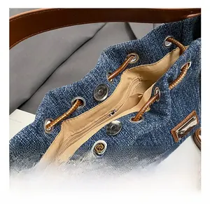 Macro view of blue denim bucket bag with silver eyelets and brown leather drawstring