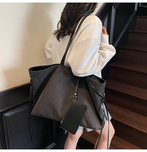 Dettaglio della grande borsa tote in tela nera con coulisse laterali e mini astuccio abbinato