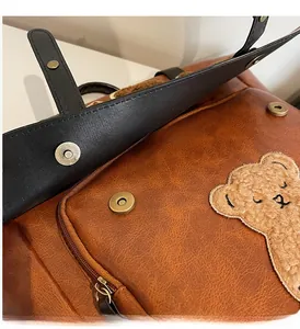 Close-up of vintage brown PU leather bag with bear embroidery and bronze magnetic clasp