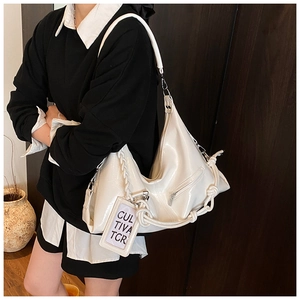 Close-up of white hobo bag with braided rope detail and polished synthetic leather texture