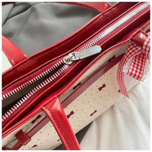 Vue macro de la fermeture éclair argentée et couture du manche en cuir verni rouge