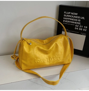 Detail of yellow leather Boston bag with Love 105 embossed text and metal zipper