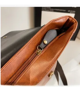 Detail view of smooth metal zipper and brown leather stitching on vintage backpack