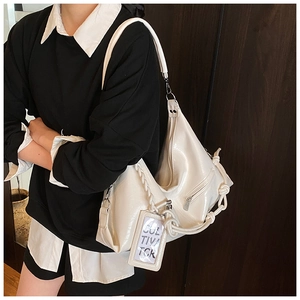 Close-up of white glossy leather tote bag with woven strap and side zipper detail