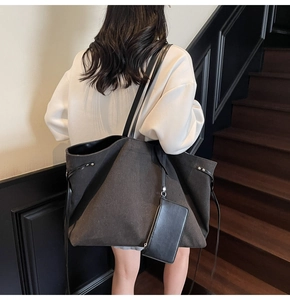 Dettaglio della grande borsa tote in tela grigio scuro con sottili spalline nere e pochette