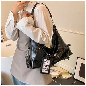 Side view of black glossy leather tote bag with knotted strap and zipper detail