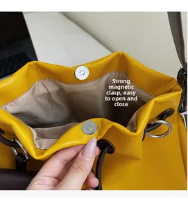 Detail of yellow leather bucket bag featuring a secure magnetic snap closure and drawstring