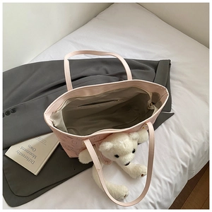 Detail view of pink faux leather tote bag with interior zipper pocket and plush bear charm