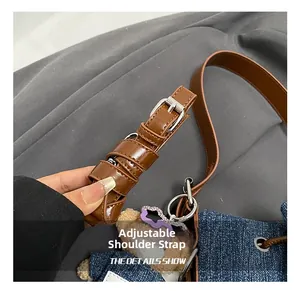 Detail of adjustable leather shoulder strap with silver buckle on denim tote bag