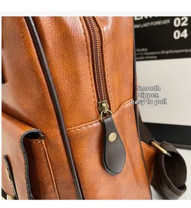 Detail of smooth copper-gold zipper and brown pebble leather texture on backpack