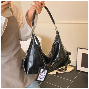Detail of black glossy crinkled leather hobo bag with silver buckles and side zip pocket