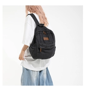 Side view of a vintage black denim backpack showing its large capacity and texture