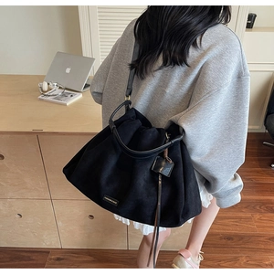 Detail of black pleated tote bag with metal logo on high-quality suede-like material