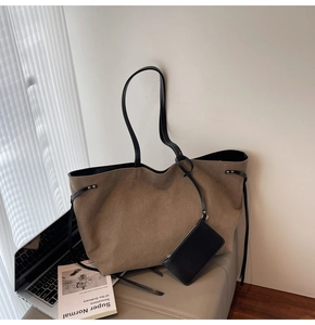 Dettaglio della borsa tote in tela con manici in pelle nera e piccola tasca con cerniera
