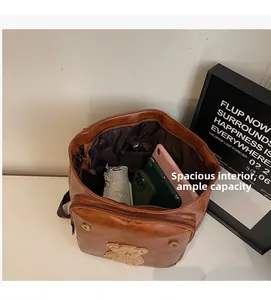 Detailed view of spacious interior of brown leather backpack with cute teddy bear patch