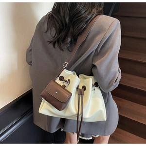 Detail view of cream drawstring bucket bag with contrast brown mini pouch accessory
