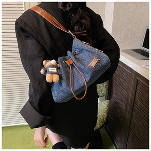 Detail of denim bucket bag with brown leather drawstring and cute bear pendant charm