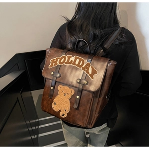 Close-up of vintage brown leather backpack with HOLIDAY teddy bear patch detail