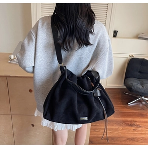 Detail of black pleated tote bag with FASHION & BAG lettering and suede texture