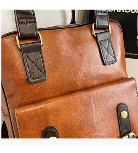 Detail of brown leather backpack featuring gold hardware and decorative cross stitching
