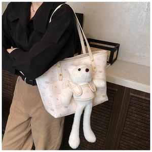 Detail of off-white tote bag with cartoon bear print and cute plush bear charm accessory