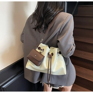 Detail of cream drawstring bucket bag with brown mini coin purse and shoulder strap