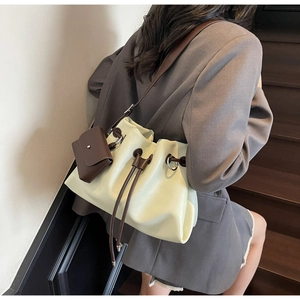 Detail of drawstring bucket bag in light green with contrast brown mini pouch accessory