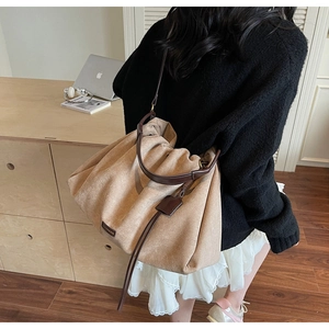 Detail of beige tote bag with pleated design and brown leather handle in a cozy room