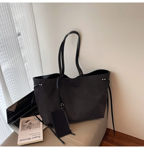 Dettaglio di una grande borsa tote in tela nera con coulisse e astuccio su una sedia