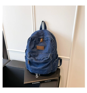 Detail of blue denim backpack with brown leather patch on black fashion books