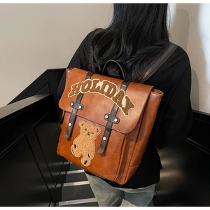 Detail of brown vintage PU leather backpack featuring holiday bear embroidery and buckle straps