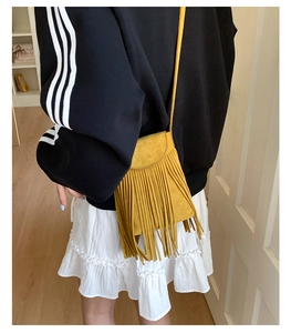 Detailed close-up of vibrant yellow tassel crossbody bag in soft faux suede finish