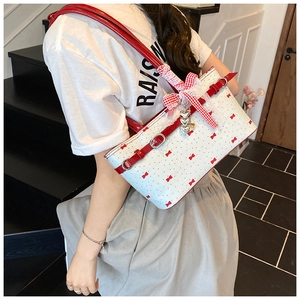 Détail du sac oreiller rose avec imprimé nœud rouge et pendentif cœur en studio