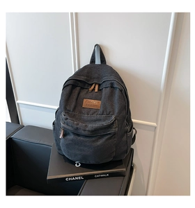 Detail of vintage dark grey denim canvas backpack with brown leather patch and metal zipper