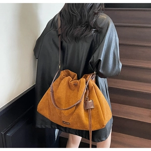 Macro detail of brown suede tote bag with drawstring closure and dark leather straps