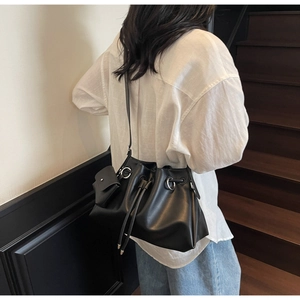 Detail of minimalist black drawstring bucket bag with silver ring hardware and pouch