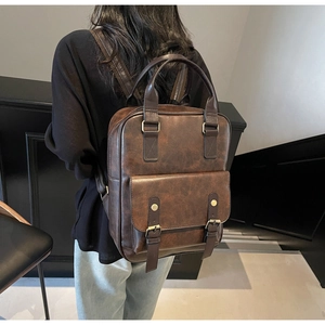 Rear view of a vintage dark brown leather backpack on model showing strap details