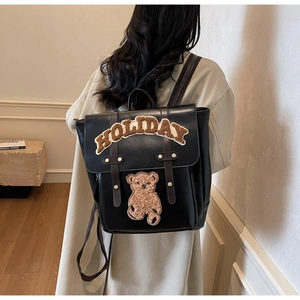 Detail view of black PU leather backpack featuring plush holiday letters and bear motif