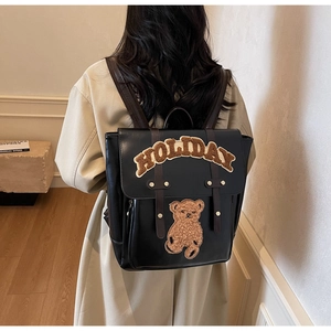 Detail of black faux leather backpack with brown sheepskin HOLIDAY letters and bear patch