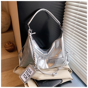 Detail of silver metallic hobo bag with woven handle and texture on beige background