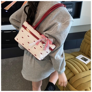 Détail du sac à main blanc à nœuds rouges avec pendentif en dentelle et breloque coeur