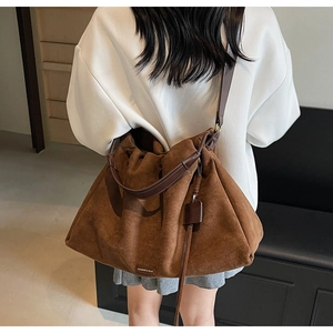 Detail of a large brown suede tote bag featuring pleated texture and leather straps