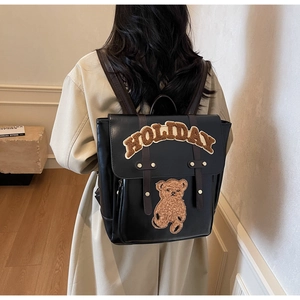 Rear view of vintage black backpack with plush teddy bear and Holiday embroidery