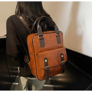 Detail of vintage brown faux leather backpack with matte texture and metallic buckle