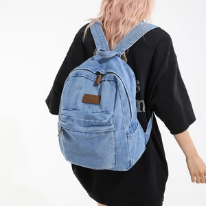 Vintage light blue denim backpack with leather patch and side pockets for casual travel