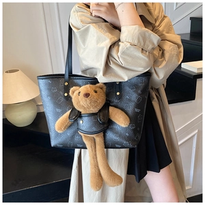 Detail of cute tote bag with brown plush bear and black litchi grain texture