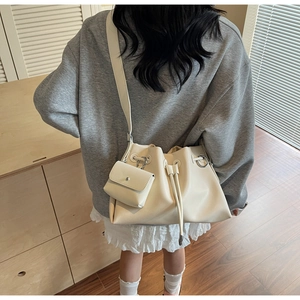 Detail of minimalist cream bucket bag with drawstring closure and matching mini pouch