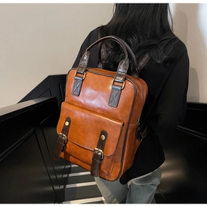 Detail of vintage brown leather backpack showing dual-use straps and retro metal buckles