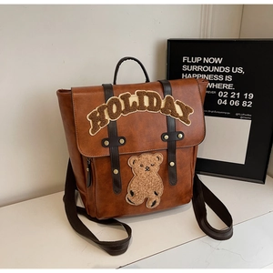 Detail of vintage brown backpack with plush Holiday lettering and teddy bear patch