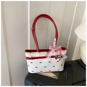 Détail du sac polochon blanc avec nœuds rouges, dentelle et pendentif cœur